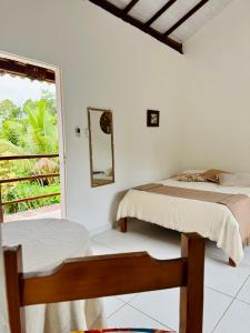 a white room with two beds and a window at Mandacaru Pousada in Porto Seguro