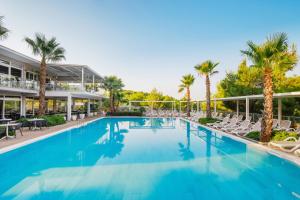 a large swimming pool with chairs and palm trees at Gava Waterman Island Cottages - All Inclusive in Milna +33 photos
