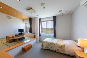a bedroom with a bed and a desk and a tv at Sunhills Sarai in Shintotsukawa