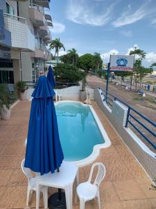 an umbrella and chairs next to a swimming pool at Hotel Mirante Da Ilha in Alter do Chao