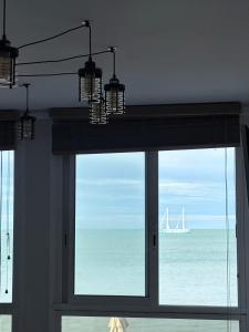 a window with a view of the ocean and a sail boat at Gîte Les pieds dans l eau à Fécamp avec pleine vue mer in Fécamp