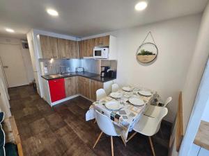 een keuken met een tafel en witte stoelen en een keuken met een tafel en stoelen bij Appartement rénové et tout confort · Au cœur de la station · Animaux admis - FR-1-181-906 in Plagne Bellecote