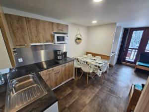 een keuken met een tafel met stoelen en een magnetron bij Appartement rénové et tout confort · Au cœur de la station · Animaux admis - FR-1-181-906 in Plagne Bellecote +7 foto's