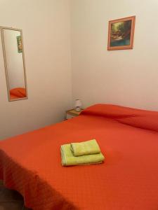 Una cama roja con una toalla verde encima en Maluma, en Santa Maria Navarrese