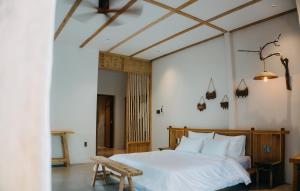 a bedroom with a white bed and a wooden bench at Nong Lam Ecolodge in Linh Xuân Thôn +84 photos