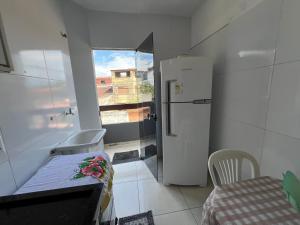 una pequeña cocina con nevera y ventana en Apto Ninho Sereno em ilheus, en Ilhéus
