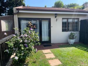 5 OYSTER COTTAGE في ديربان: منزل أبيض صغير مع باب أسود