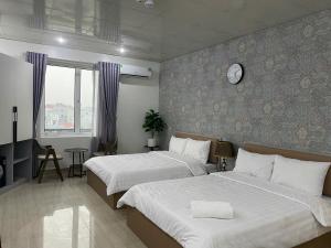 a bedroom with two beds and a clock on the wall at Khách sạn Sole'a VĨNH YÊN in Vĩnh Phúc