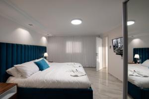 a bedroom with a large bed with a blue headboard at וילה מילגרוס - וילה עם בריכה פרטית מחוממת ומקורה - נוף לים in ‘Ein Ya‘aqov