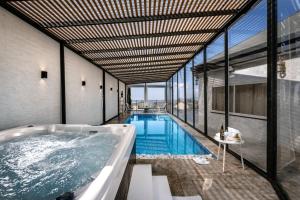 a swimming pool with a tub in a building at וילה מילגרוס - וילה עם בריכה פרטית מחוממת ומקורה - נוף לים in ‘Ein Ya‘aqov +11 photos