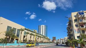 a city street with palm trees and a yellow car at T2 Cosy & Central Akid Lotfi in Oran