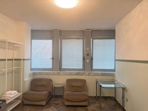 zwei Stühle und ein Tisch in einem Zimmer mit Fenstern in der Unterkunft HHBB hotel in Padua + 2 Fotos