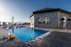 a swimming pool with rocks in front of a house at וילה מילגרוס - וילה עם בריכה פרטית מחוממת ומקורה - נוף לים in ‘Ein Ya‘aqov