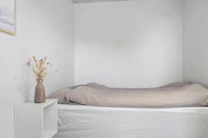 Un dormitorio blanco con una cama y un jarrón en una mesita de noche en 1302-Thisted-Havstokken-30-1, en Thisted