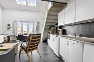 a kitchen with white cabinets and a table and chairs at 212-Vestervig-Havnevej-1-lejl-12 in Vestervig