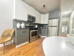 a kitchen with white cabinets and stainless steel appliances at Dream Home Close to the Center of NYC in Mott Haven