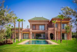 a large house with a swimming pool and palm trees at Villa Jumeirah M Luxury & Spacious Pool in Marrakech