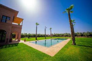 a swimming pool in a yard with a palm tree at Villa Jumeirah M Luxury & Spacious Pool in Marrakech