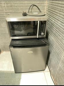 a microwave sitting on top of a refrigerator at Cozy Apartment in Kololi
