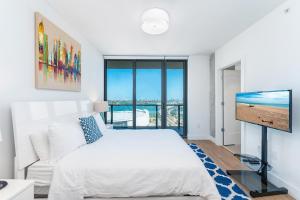 a bedroom with a white bed and a flat screen tv at Global Luxury Suites Miami Worldcenter in Miami
