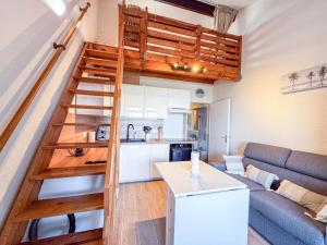 a living room with a staircase leading up to a loft at Escale aux tropiques - Vue mer in Saint Cyprien Plage