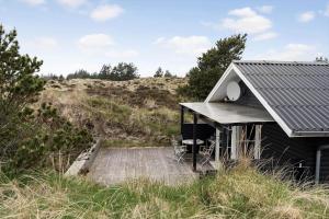 a small house with a wooden deck in a field at 930-Thisted-Liusborg-Sti-28 in Torsted