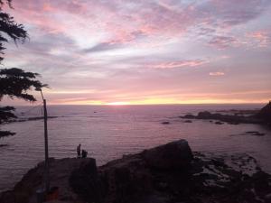 Um homem em pé sobre uma rocha perto do oceano ao pôr do sol. em Playas de Quintero em Quintero