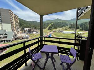 a table and two chairs on a balcony with a view at Appartement 2 pièces Griou 52 in Le Lioran