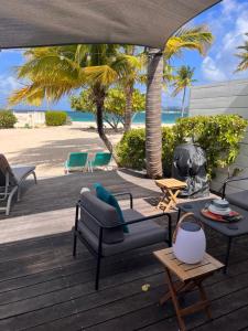 a patio with a couch and a table and palm trees at Sole e Mare NBBC sur la plage de Baie Nettlé in Baie Nettle