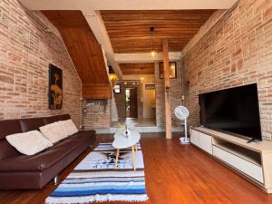 a living room with a brown couch and a brick wall at The Canopy house Private cozy stay Pai Mountains in Pai