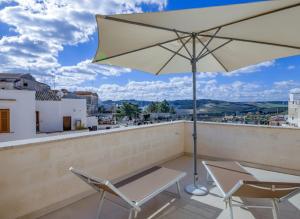 a patio with two chairs and an umbrella on a roof at Palazzo Fondo Vico - Affitti Brevi Italia in Gravina in Puglia