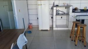 a kitchen with a white refrigerator and two stools at Casa em Itapucu SC a 200mts do trapiche in Araquari