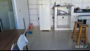 a kitchen with a white refrigerator and two stools at Casa em Itapucu SC a 200mts do trapiche in Araquari