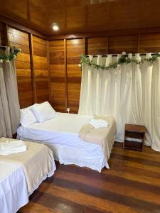 马瑙斯Amazon Tucuna Resort的配有白色窗帘的客房内的两张床 更多8张照片