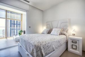a white bedroom with a bed and a large window at Intempo by Holuxe - 034 - 3rd floor in Benidorm