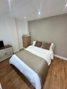 a bedroom with a large bed and a wooden floor at Kettering Railway Lodge in Northamtonshire