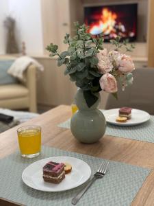 a table with a plate of cake and a vase with flowers at Infinity Apartman in Esztergom