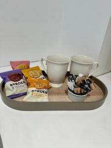 a tray with snacks and two cups on a table at Kettering Railway Lodge in Northamtonshire