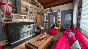 Oceana Suites San José de Maipo في إل كانيلو: غرفة معيشة مع أريكة حمراء ومدفأة