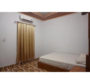 a bedroom with a bed and a shower curtain at Hotel O Pondom Danu 77 in Kendari +17 photos