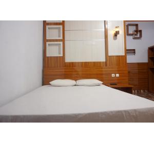 a bed with two white pillows in a room at Hotel O Pondom Danu 77 in Kendari