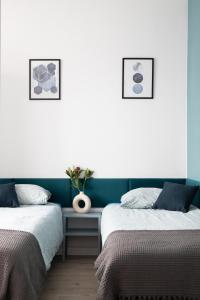 a bedroom with two beds and a vase on a table at ADLER Room Suite in Łódź