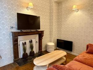 een woonkamer met een tv boven op een open haard bij La Grande escapade T12 in Troyes