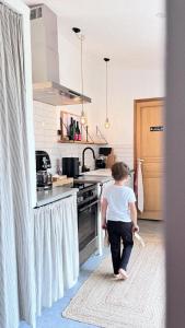 een jong kind dat in een keuken met een fornuis loopt bij Maison 1634 - petit-déjeuner offert, parking, centre ville à pied, piscine, climatisation, cuisine in Pézenas +24 foto's