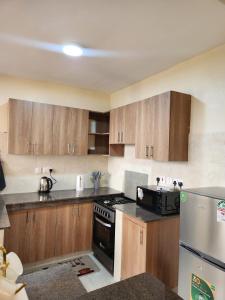 a kitchen with wooden cabinets and a stove top oven at Casaroca Stylish 2br in Nakuru