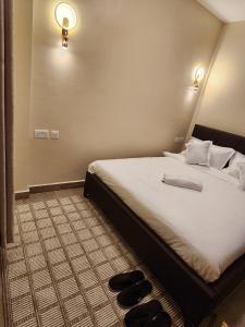 a bedroom with a large bed with black shoes on the floor at Casaroca Stylish 2br in Nakuru