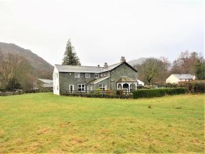 ein großes Haus auf einem Grasfeld mit einem Haus in der Unterkunft 4 Bed in Rosthwaite 86248 in Rosthwaite