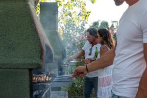 a group of people standing around a grill at Villa Serena in Rosolina Mare