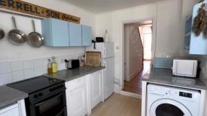 een keuken met blauwe kasten en een wasmachine en droger bij Victoria Residences in St Ives