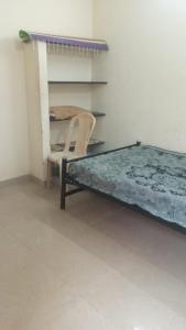 Near by Annamalaiyar temple 2 Home stay في تيروفانمالي: غرفة نوم بسرير وكرسي ورف